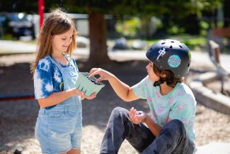 teens picking from container of blueberries in park